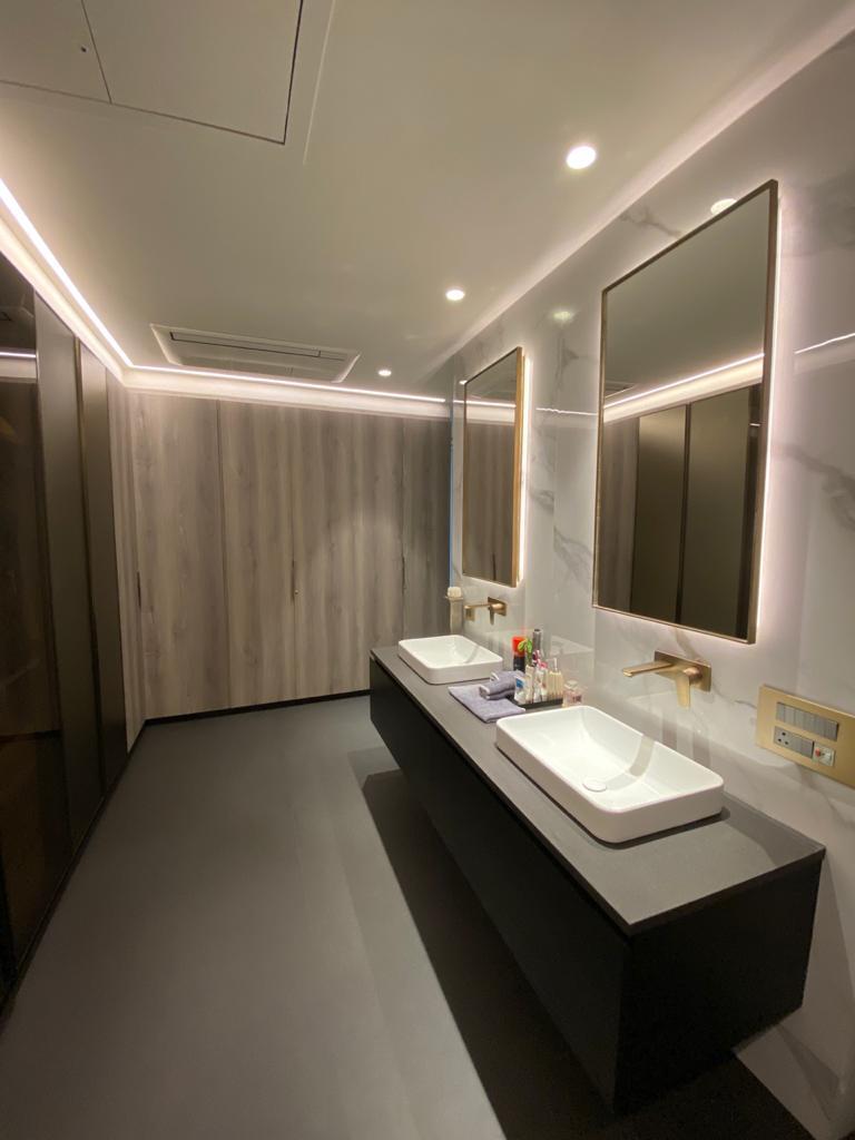 Contemporary washroom with wooden panel walls and LED mirror lighting